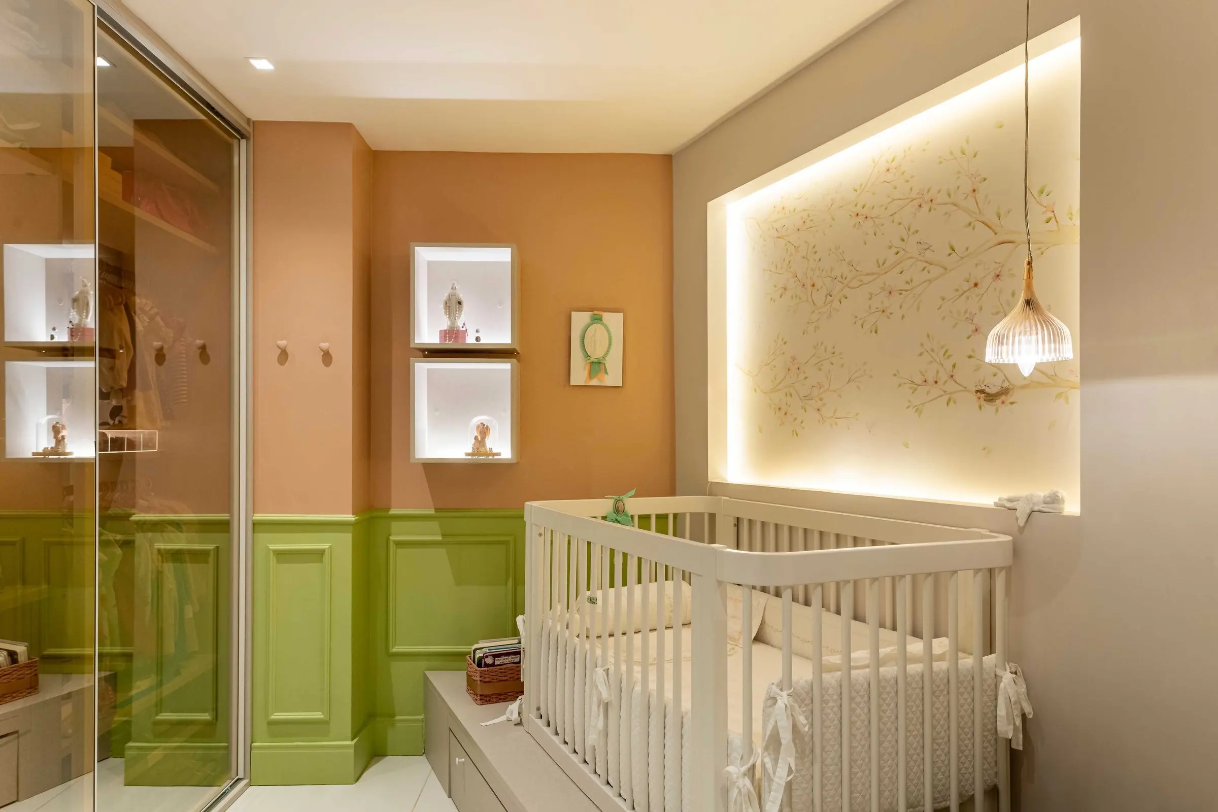 Quarto de bebê com boiserie verde, nichos iluminados e berço branco