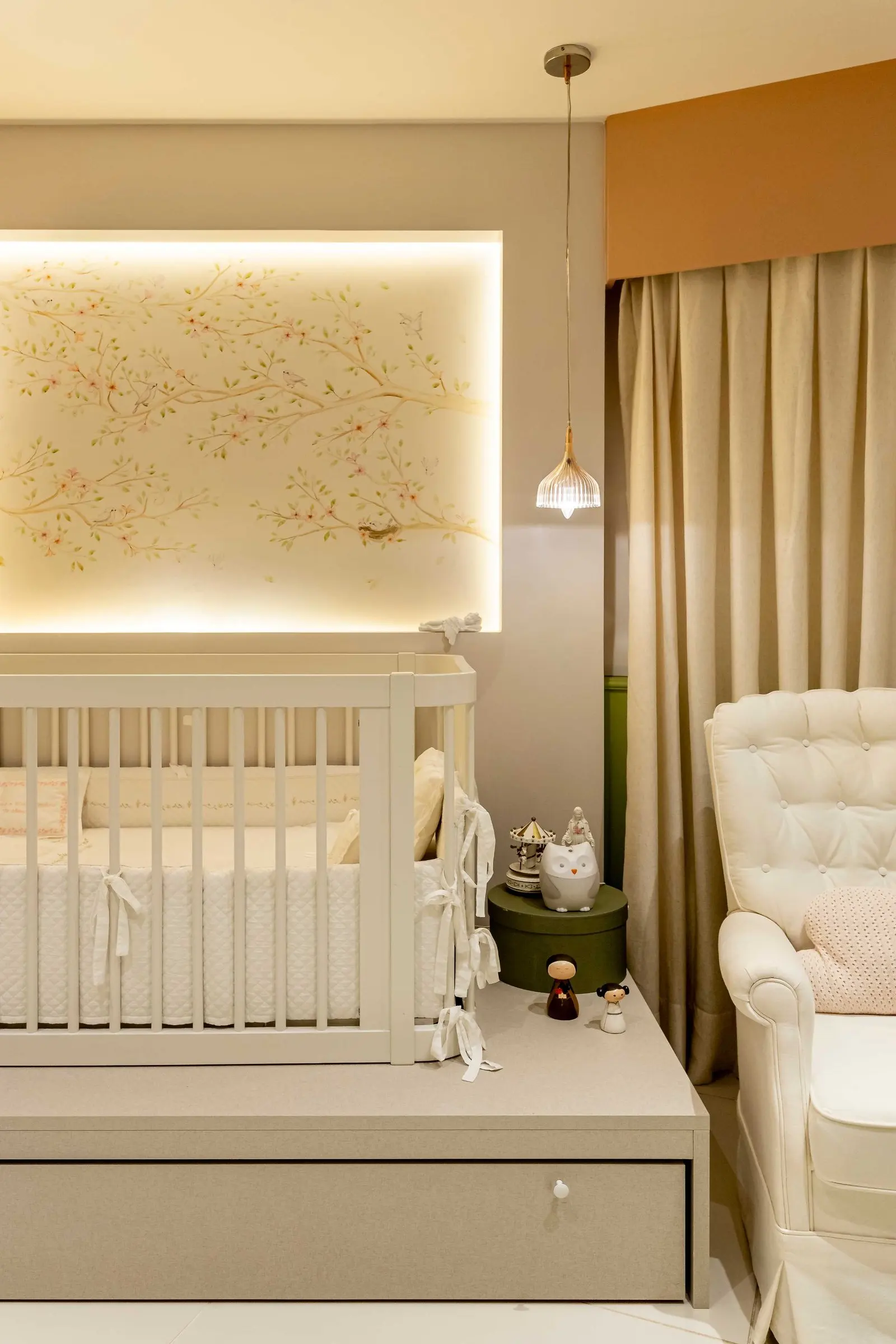 Crib beneath a lit panel with bird wallpaper
