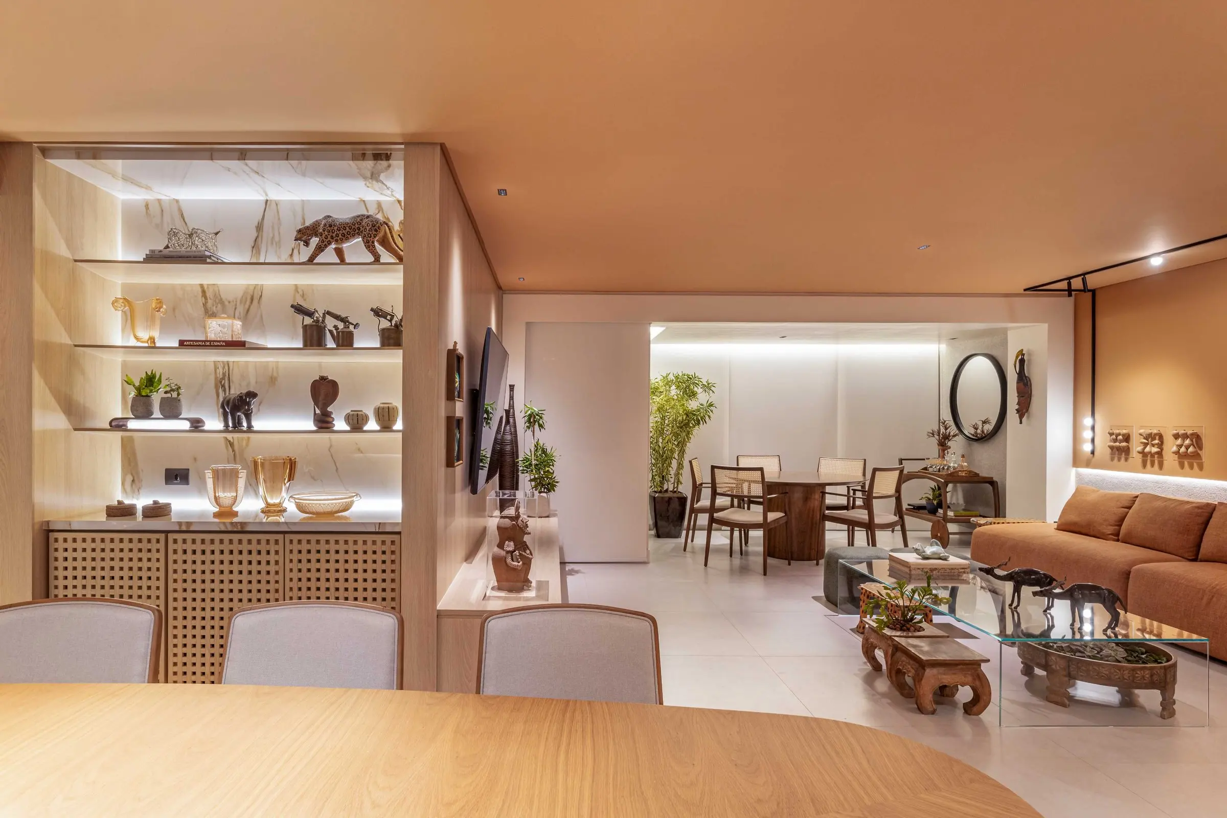 Open wooden shelving with sculptures and a view of the living room