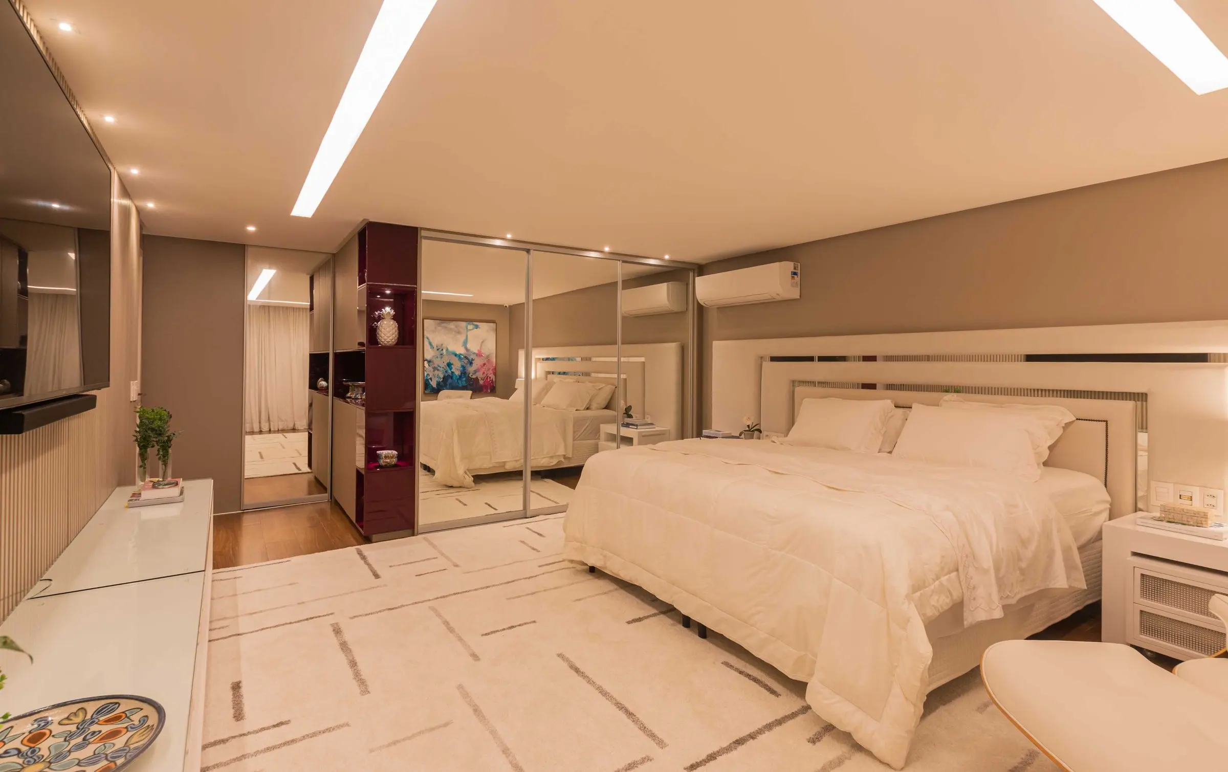 Master suite with a white bed, geometric rug and mirrored wardrobes