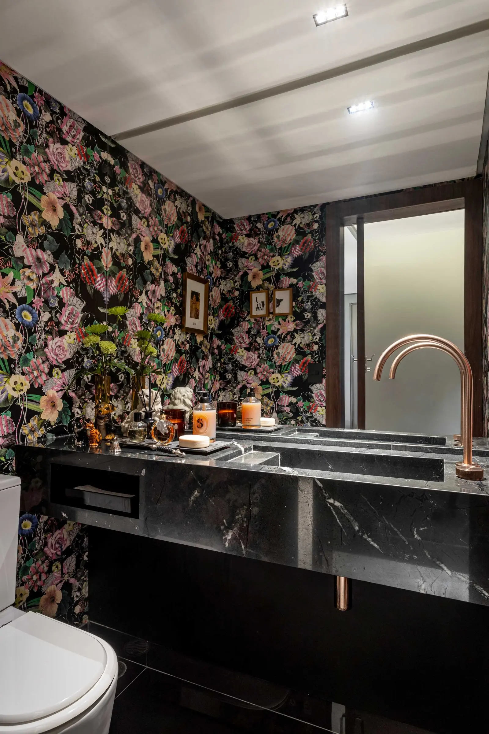 Lavabo com papel de parede floral e bancada em mármore preto